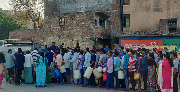 a queue of people in india waiting for water supply