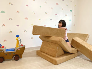 a little girl sitting on top of a play pretend pirate ship made from Playand foam blocks.