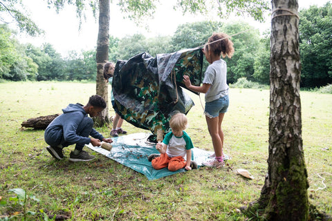 Children build dens in forest school outdoor play