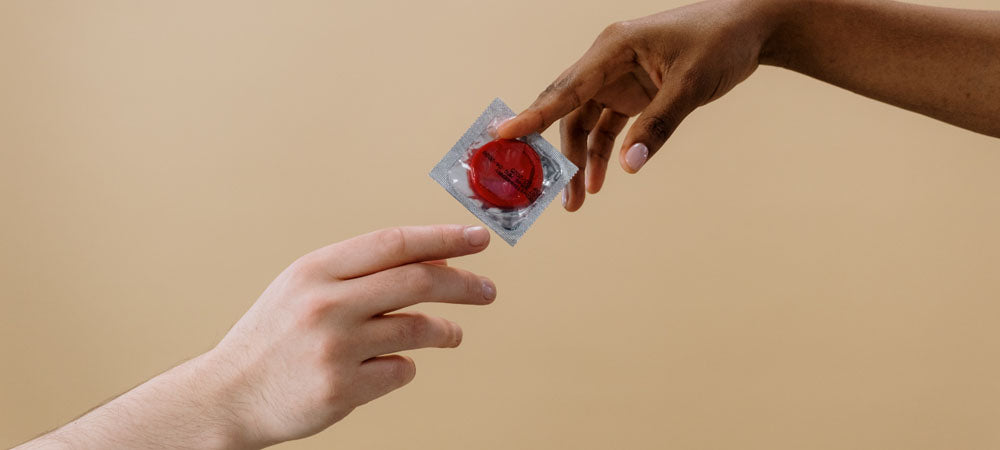 Two hands exchanging a condom
