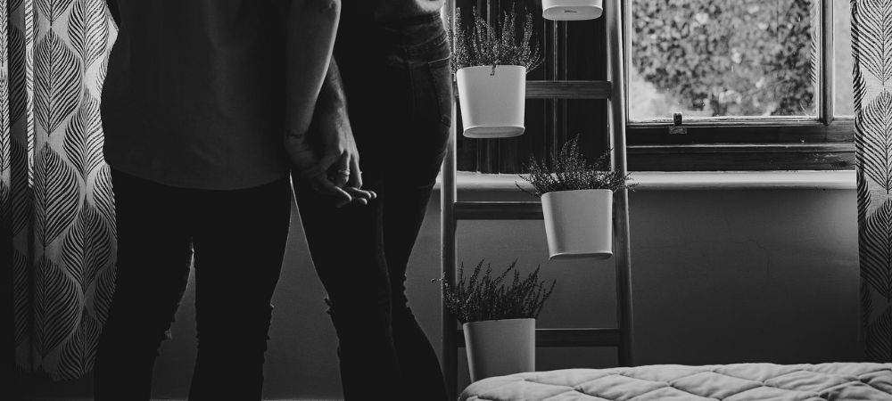 Couple standing by bed holding hands