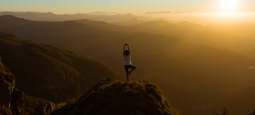 Woman performing a yoga pose on a mountain