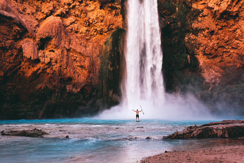 man on SUP next to waterfall