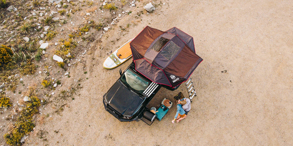 drone shot of an overlanding set up with a paddle board