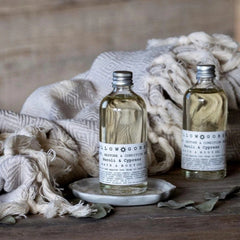 Two sustainable body oil glass bottles as Christmas gifts with blanket in background