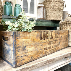 Vintage wooden crate in sustainable shop in Henley-on-Thames with green plant and blue jars