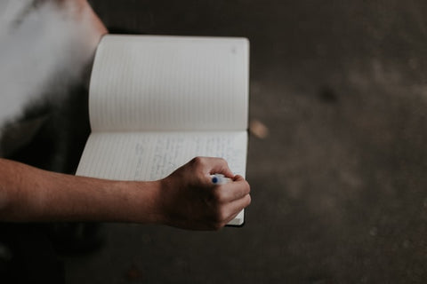 Person writing notes in journal to reduce stress