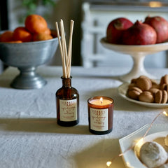 Sustainable Christmas gifts candle and reed diffuser on table with fruit in background