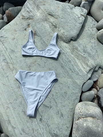 Bikini gris posé à plat sur des rochers gris et bleus au soleil