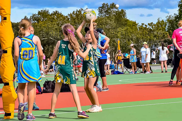 Young netballer about to shoot for the netball into the netball hoop. Kids playing netball on a sunny day