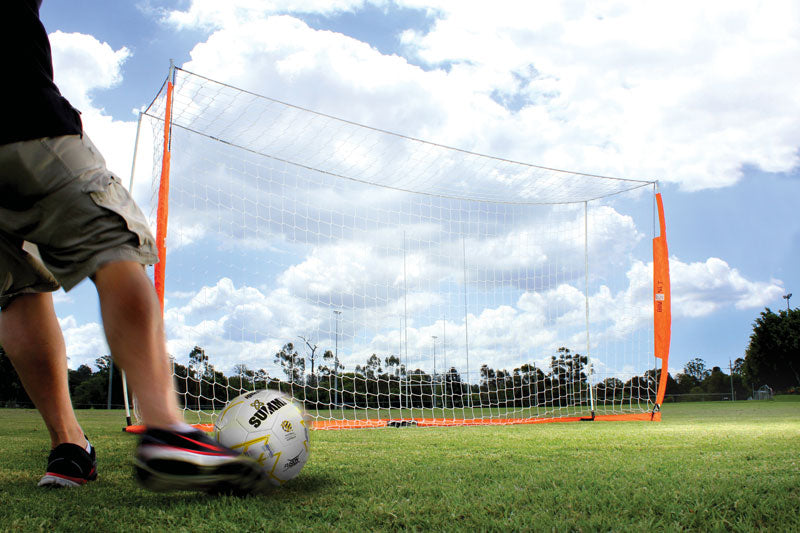 Soccer player kicking summit soccer ball into bownet barrier goal