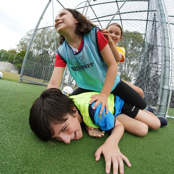 kids playing in their sports bibs. Blue bib on the girl and yellow soccer bib on the boy.