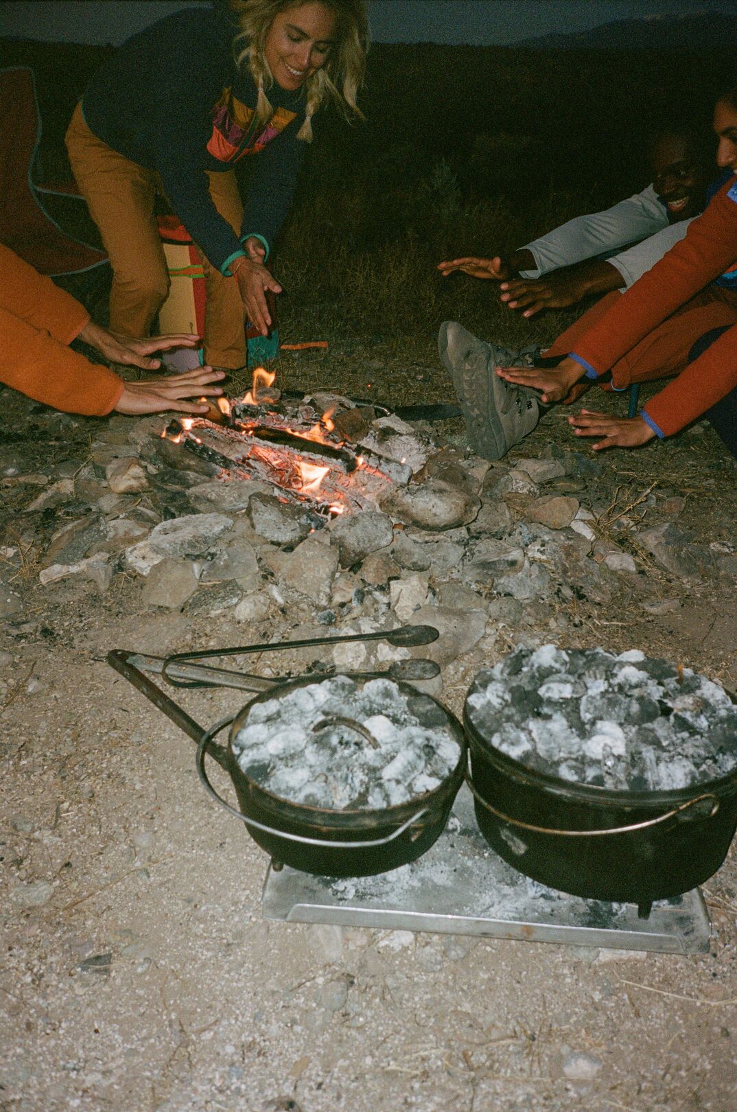 Dutch ovens cook with coals at a campsite