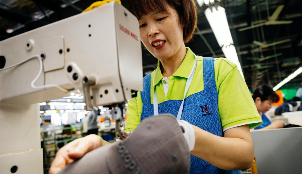 Fang Qiong Xie sews a Cotopaxi hat at ASI factory in Shanghai.