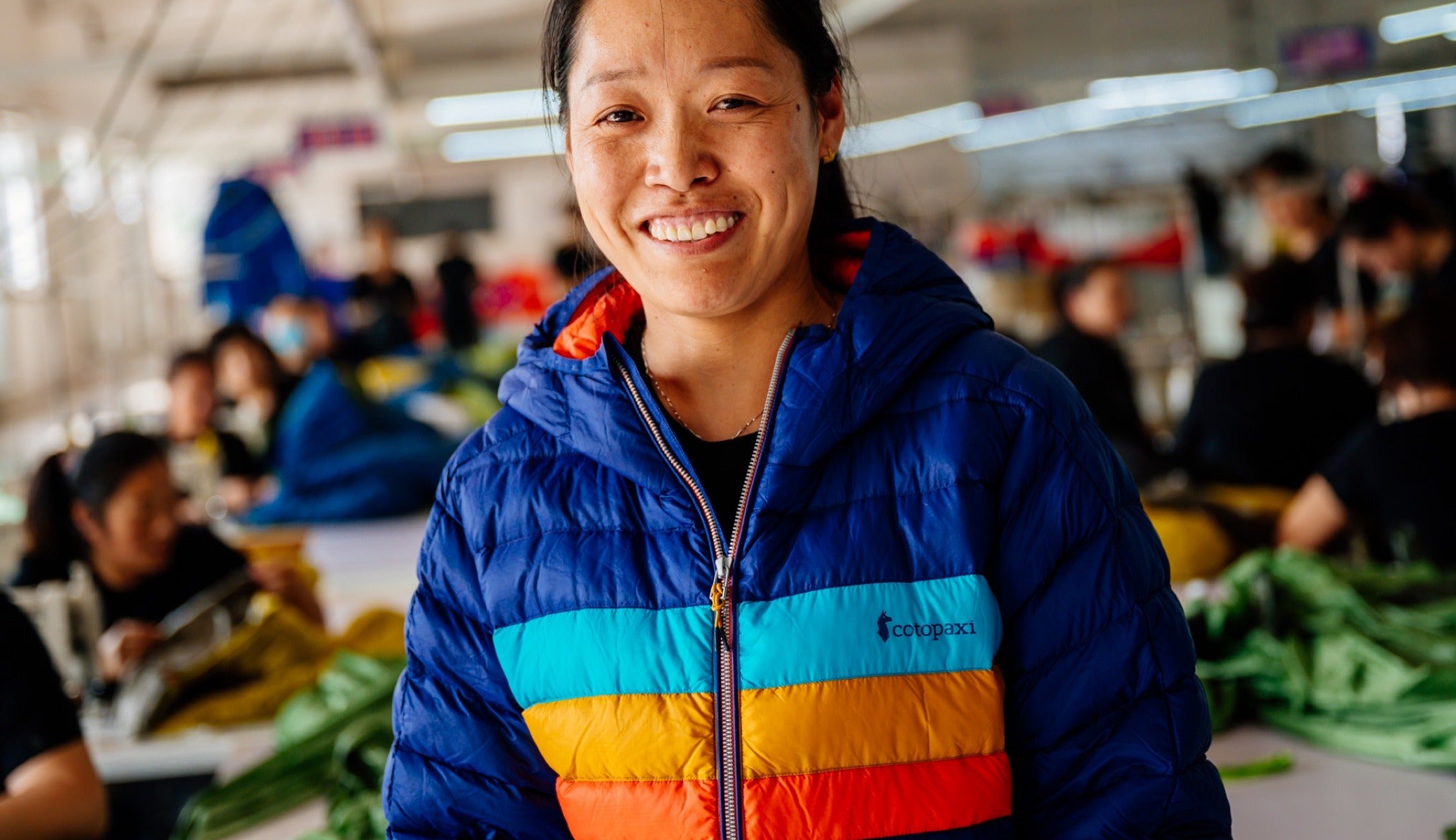 Li Xiu Zhen wears a Cotopaxi Fuego jacket on the sewing floor