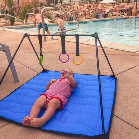 Baby laying on Lay and Play Adventure Mat on pool deck