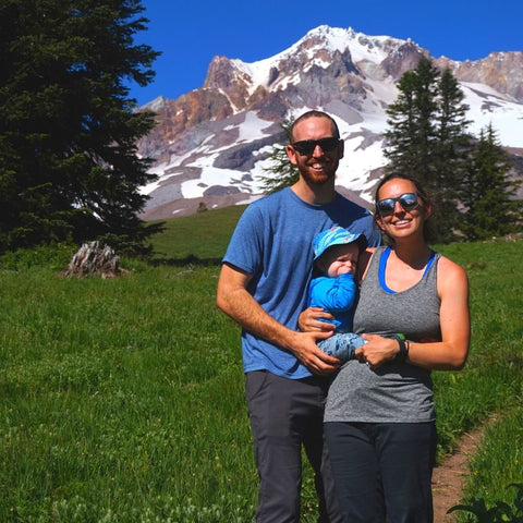 Parents and baby standing in front of mountain