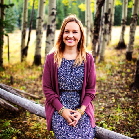 Woman sitting on a log, aspen trees in background