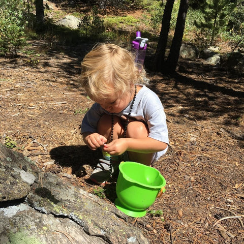 Toddler playing in dirt with bucket on hiking trail