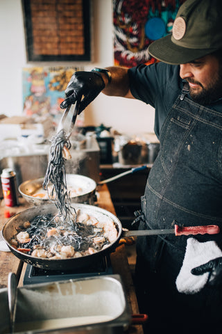 man twirling fresh linguine in a cream sauce in saute pan. pasta dinner