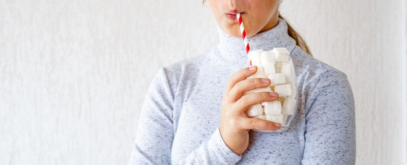 Girl drinking from a glass filled with sugar cubes