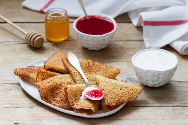 Rye and whole grain pancakes served with sour cream, honey and strawberry sauce