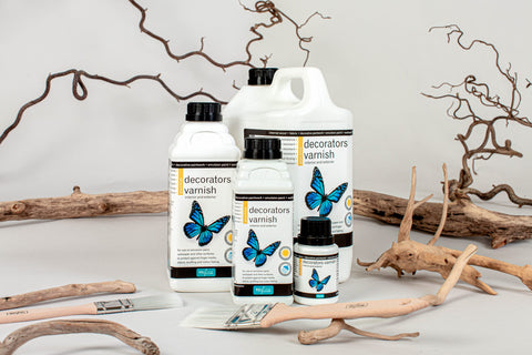 5 bottles of Polyvine varnishes. White bottles with blue butterflies. Wood background.