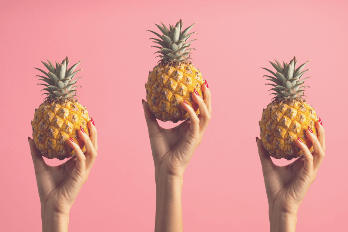 Three hands holding up a little pineapple each.