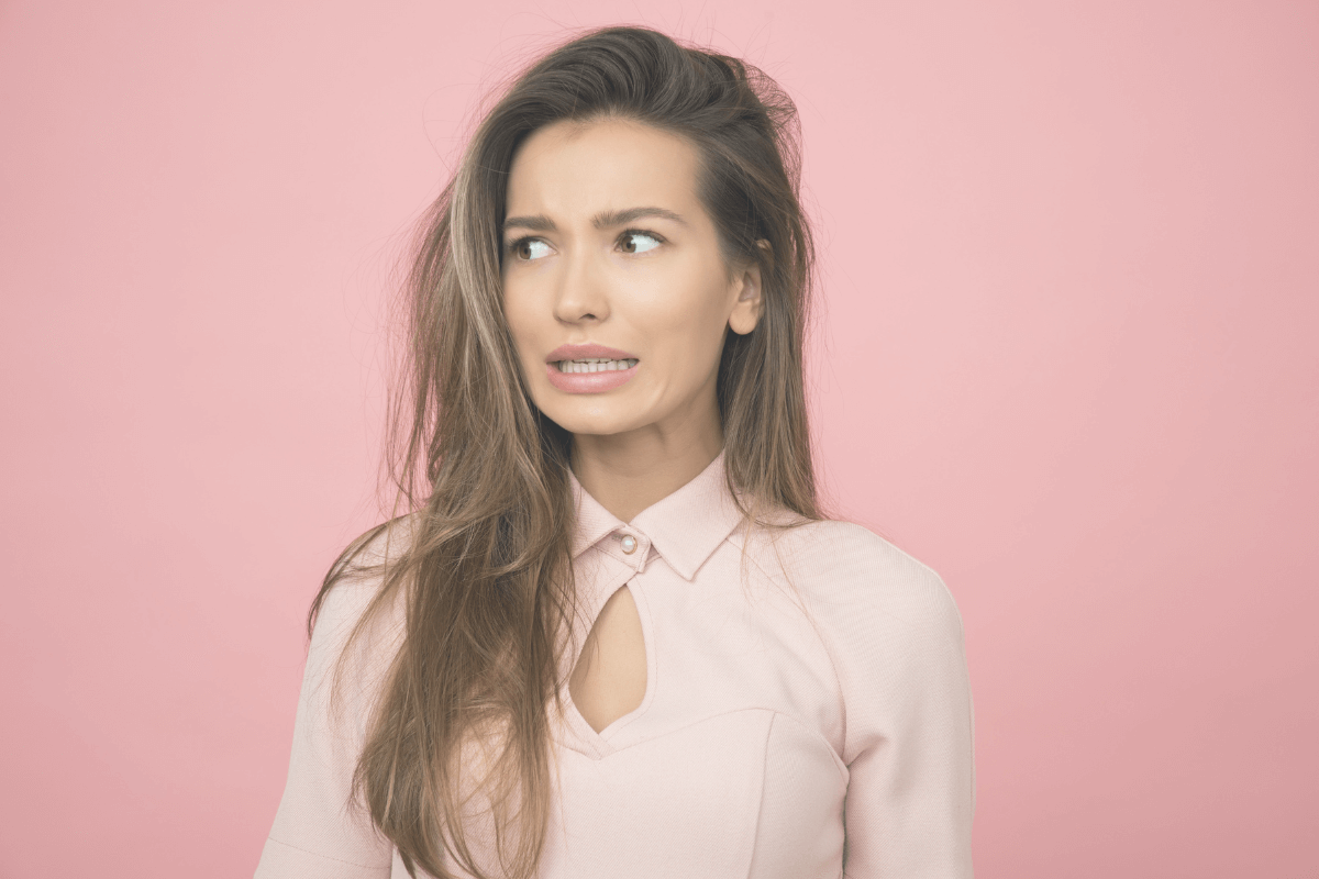 Scared looking woman with a pink background.