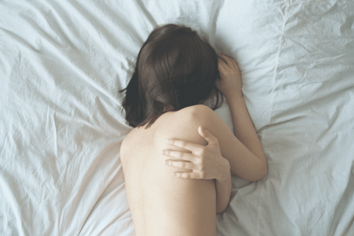 Woman lying in a bed looking down. 