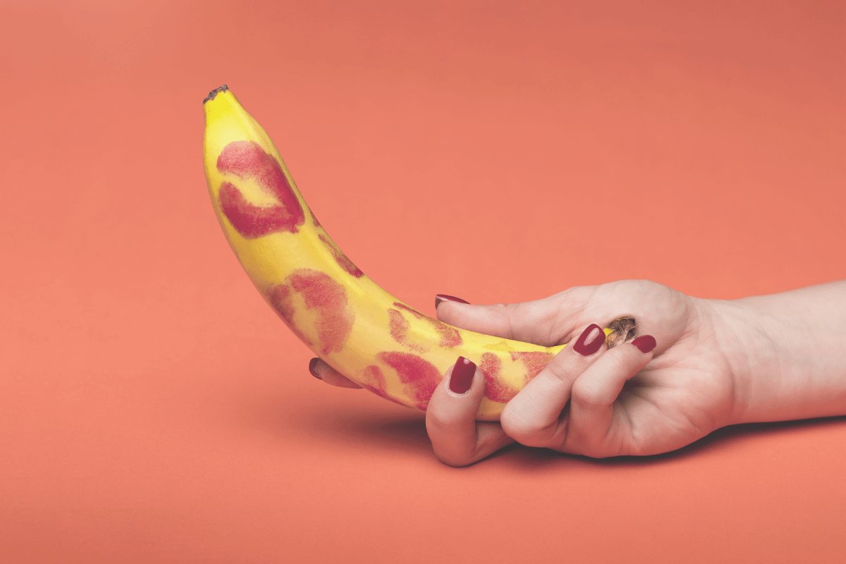 Picture of a female hand holding a banana covered in lipstick marks. 