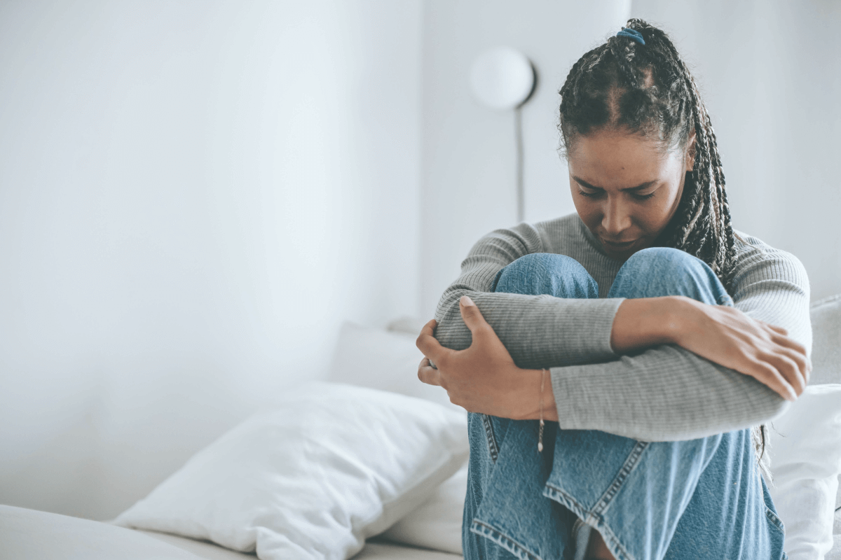 Worried looking woman sitting on a bed