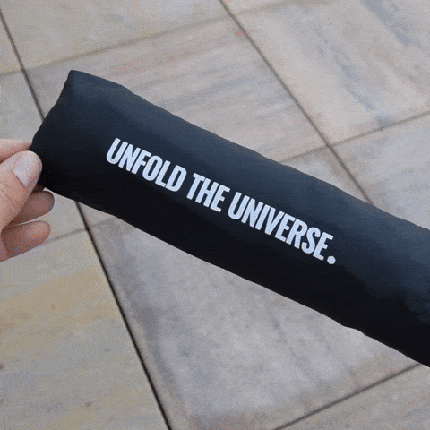 Video of JWST umbrella being unfolded. The umbrella's sleeve and strap read "unfold the universe". The canopy has a print of the James Webb Deep Field image.