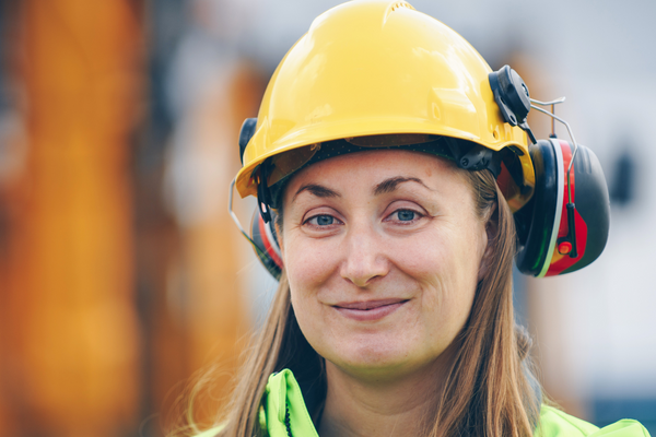 Vrouw draagt ​​een gele harde hoed met hoorbescherming headset bevestigd