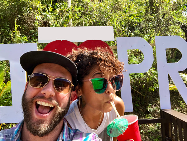 Man and woman wearing sunglasses, smiling and drinking soda.