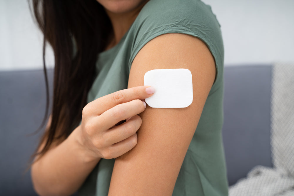 A woman putting a nicotine patch on her arm to help her quit smoking.