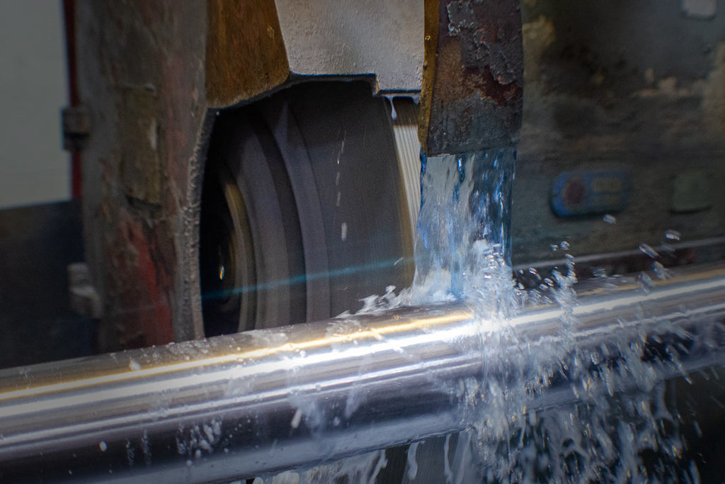 grinding wheel up against pump shaft with coolant flowing over