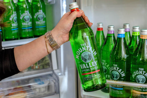 Woman grabbing Mountain Valley Spring Water from fridge