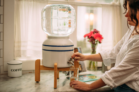 Woman pouring water into glass from glass dispenser