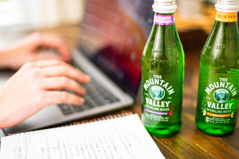 Woman working on laptop with bottles of MV