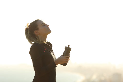 Woman meditating in the sun with a bottle of water