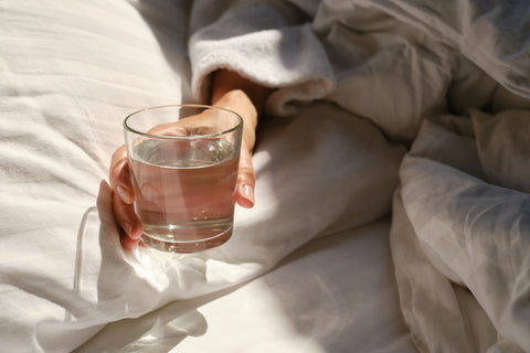 Woman holding a glass of water in bed