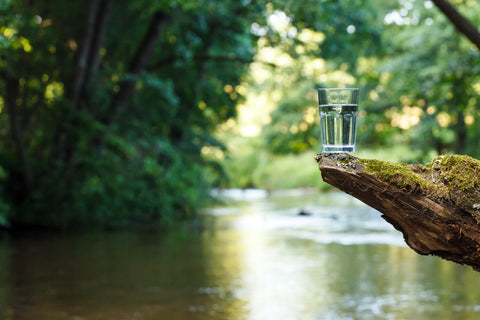 Glass of water balanced on rock above river