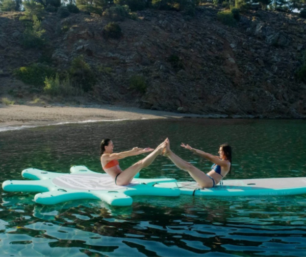 Two friends enjoy practicing yoga on their Aqua Marina yoga dock.