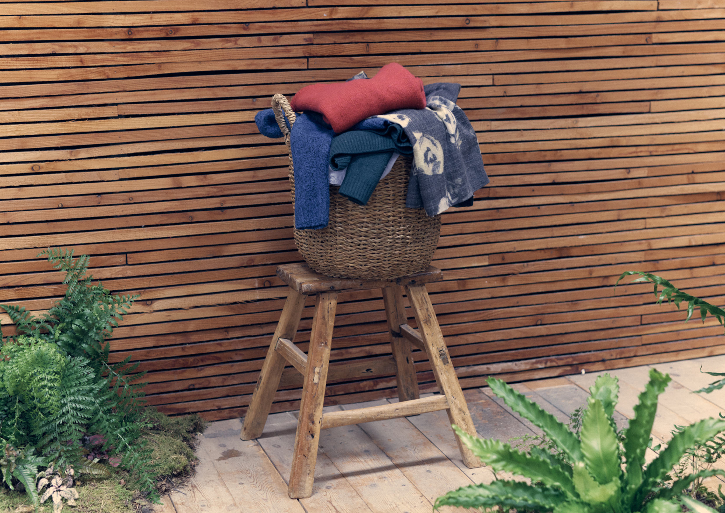 Basket on stool filled with clothes.