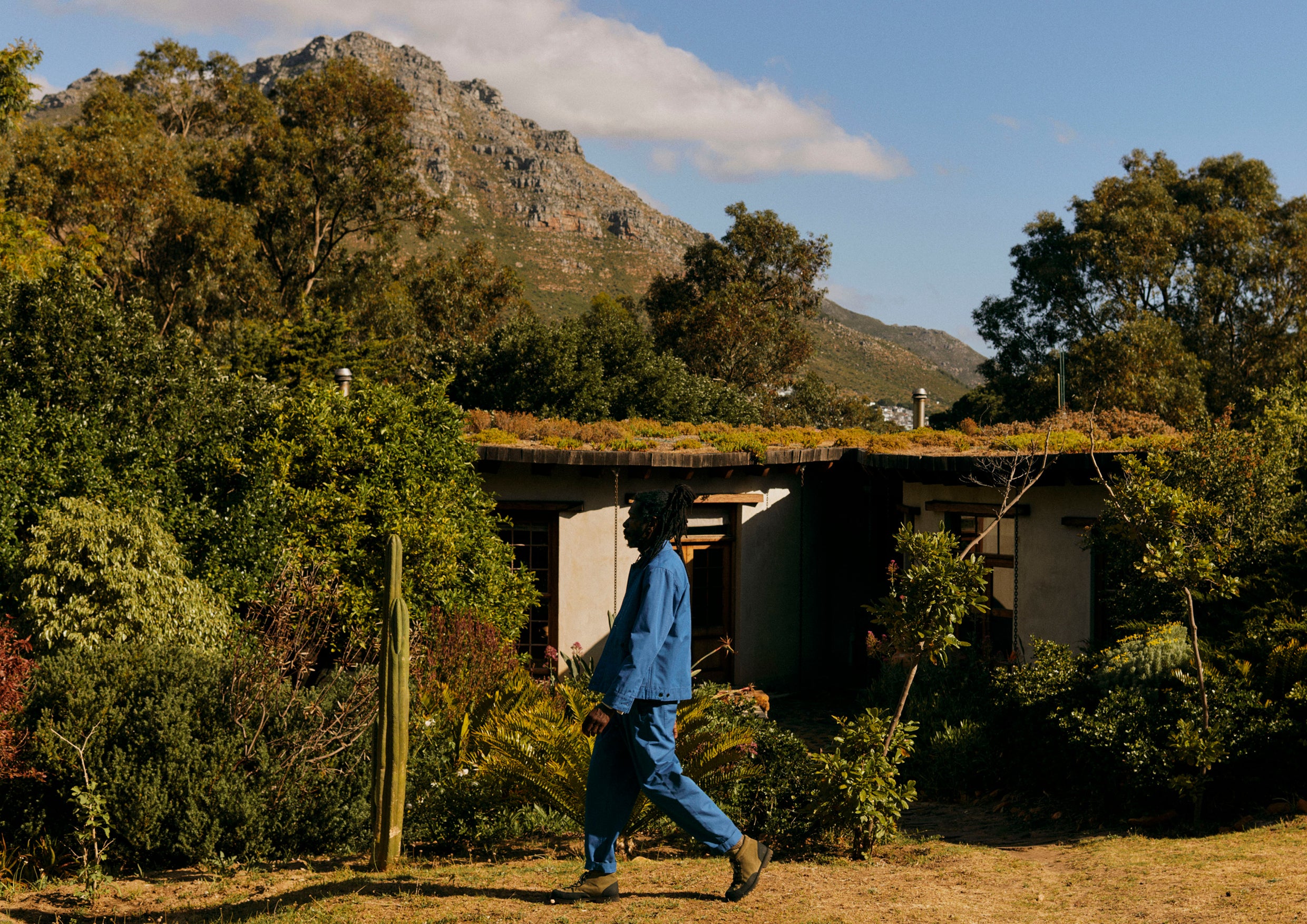 A man in a blue suit walks through nature