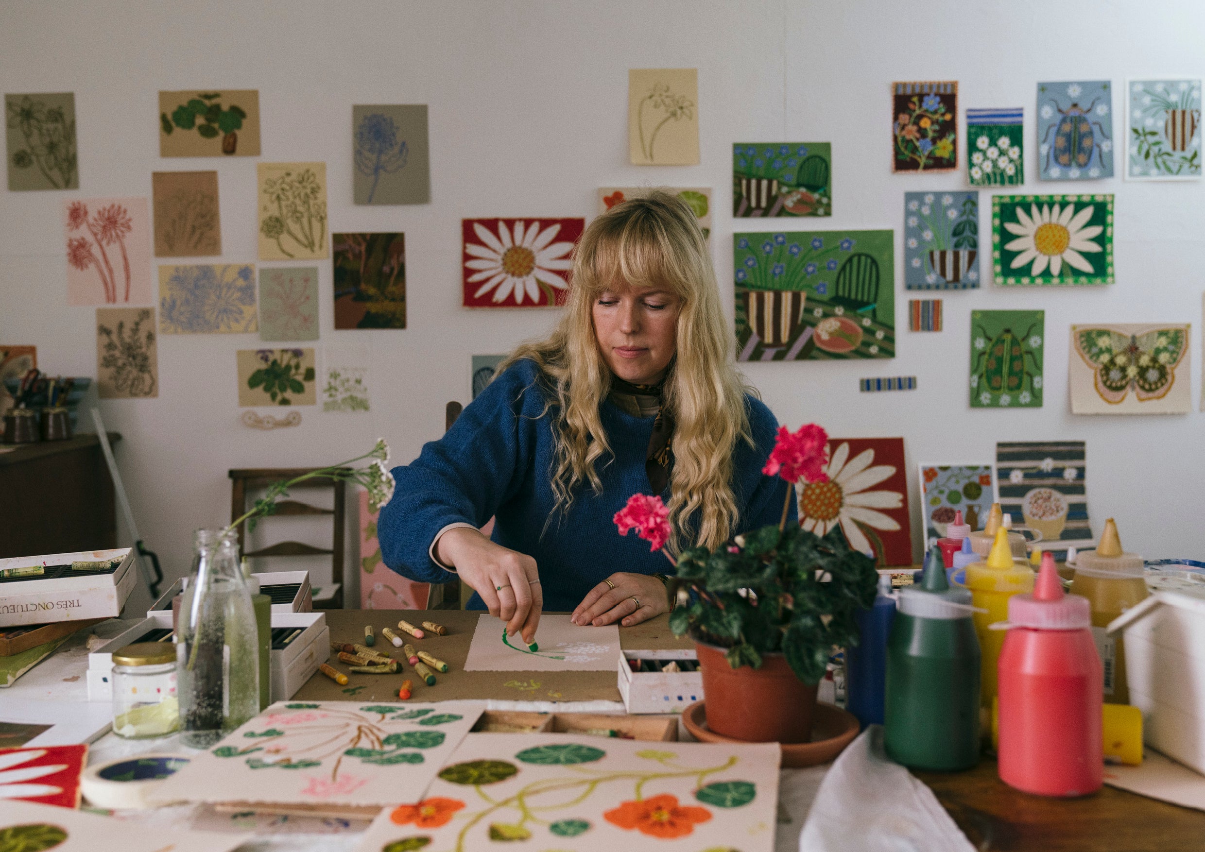Artist in a blue jumper painting in her studio