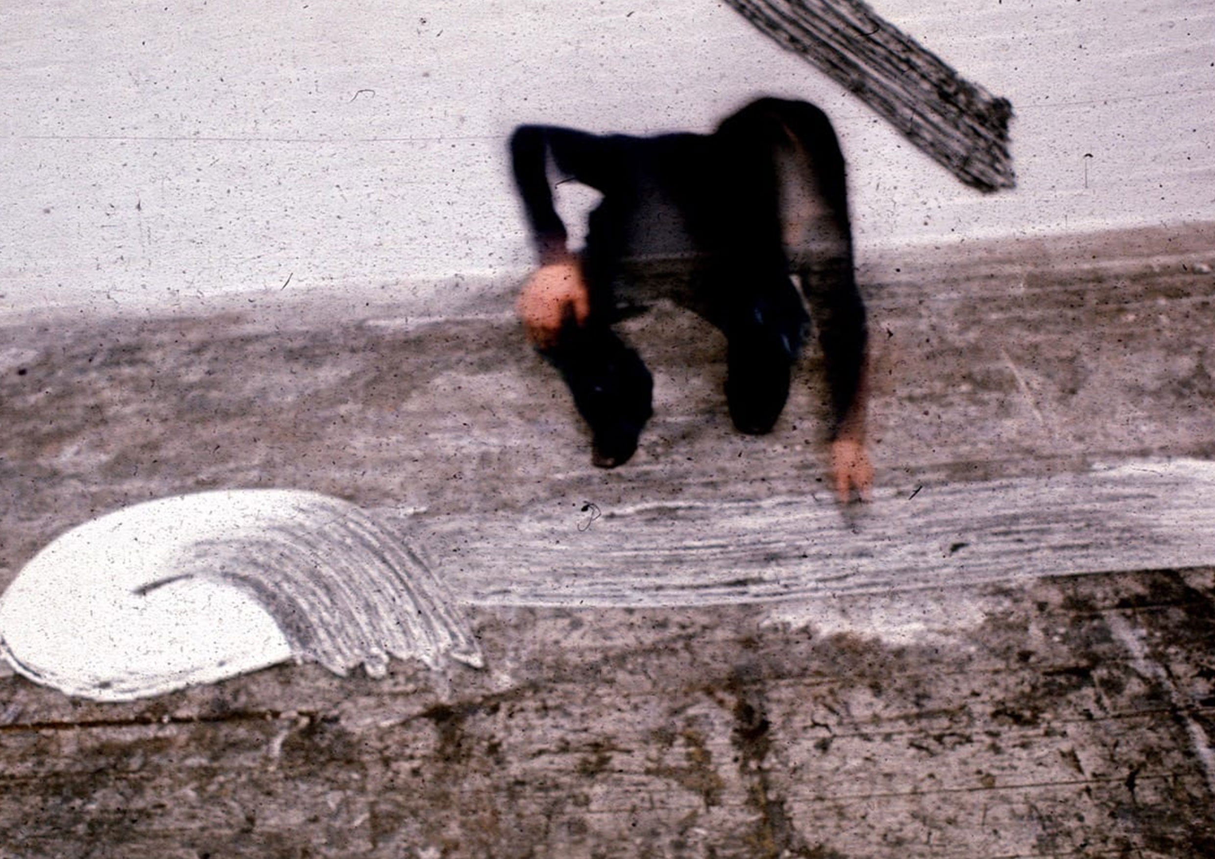 A photograph of an artist making art on the floor of their studio