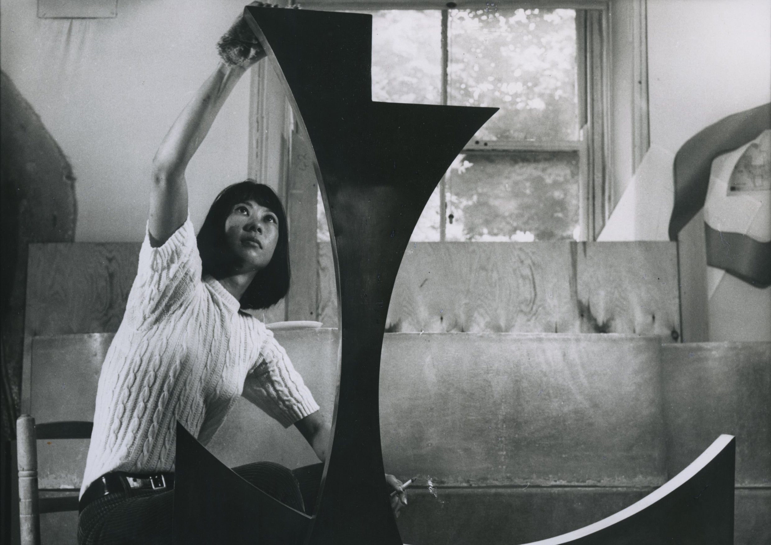 Black and white photograph of woman building an art sculpture