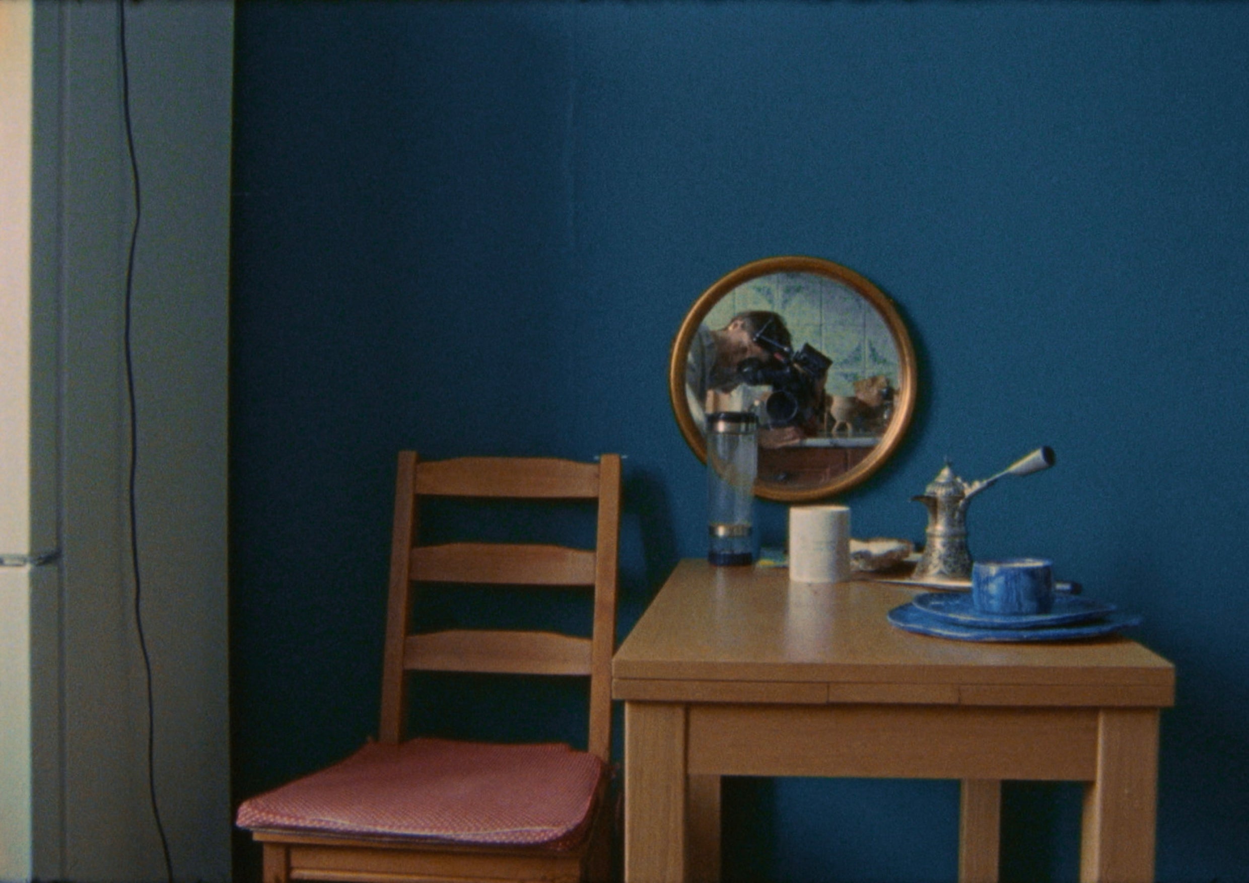 A red chair and wooden table in a room with blue walls